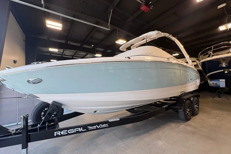 Slide: The Image of 2027 Regal LS6 boat on trailer in showroom, sleek design, under bright lighting. - 2