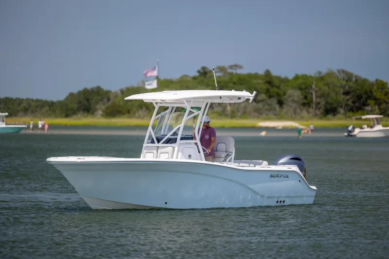 Slide: The Image of 2022 Sea Fox 228 Commander boat cruising on a calm lake with scenic background. - 2