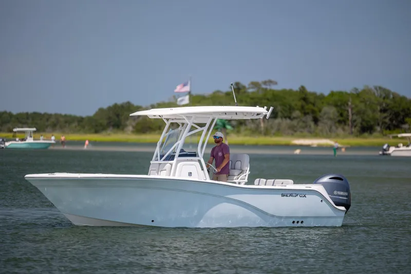 Slide: The Image of 2022 Sea Fox 228 Commander boat cruising on a calm lake with lush green shoreline. - 3