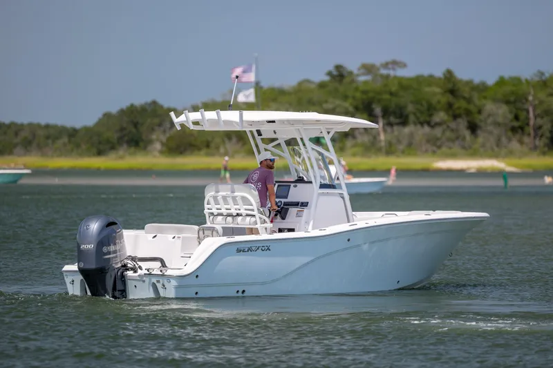 Slide: The Image of 2022 Sea Fox 228 Commander boat cruising on a calm lake with lush green shoreline. - 7