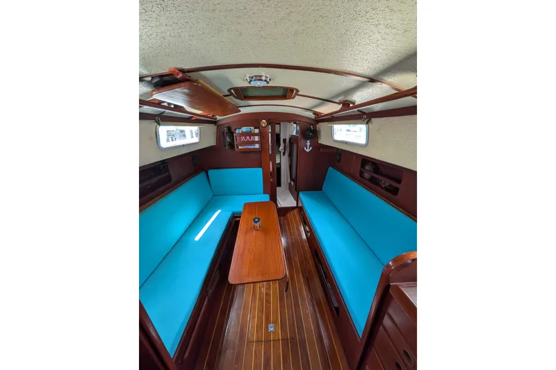Slide: The Image of Interior of 1978 Hallberg-Rassy Monsun 31 sailboat with blue seating and wooden finishes. - 31
