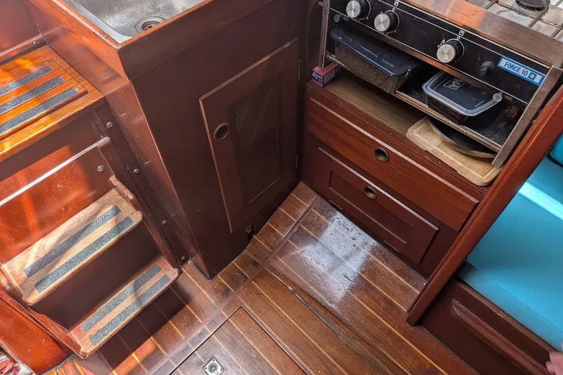 Slide: The Image of Interior of 1978 Hallberg-Rassy Monsun 31 sailboat, featuring wooden cabinetry and compact kitchen area. - 15