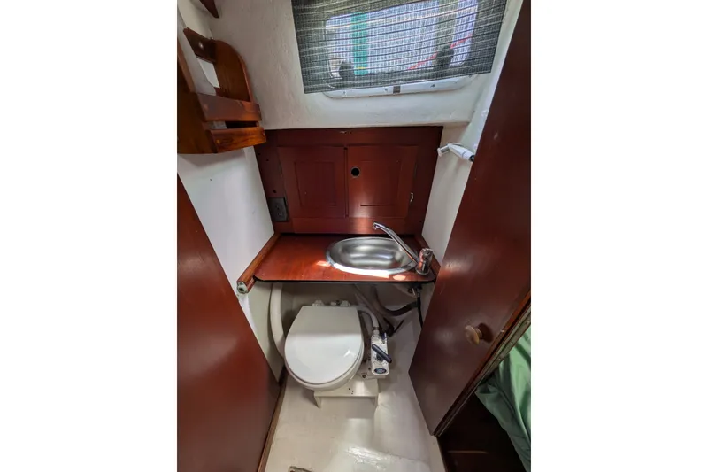 Slide: The Image of 1978 Hallberg-Rassy Monsun 31 yacht bathroom with sink, toilet, and wooden cabinetry. - 38