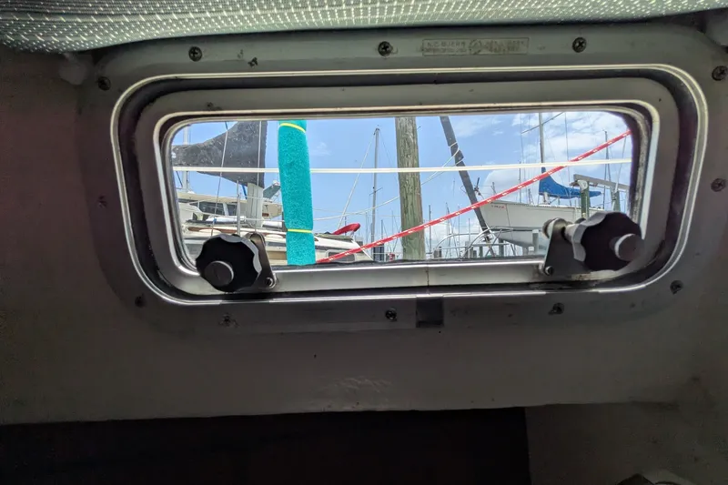 Slide: The Image of View through a Hallberg-Rassy Monsun 31 porthole, showcasing marina and sailboats, 1978 model. - 25