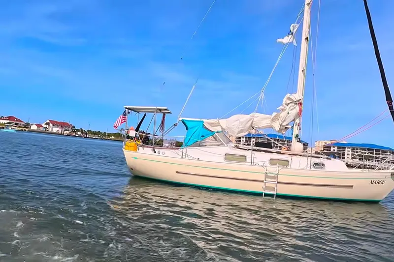 Slide: The Image of Sailboat Hallberg-Rassy Monsun 31, 1987 model, anchored in calm waters under a clear blue sky. - 2