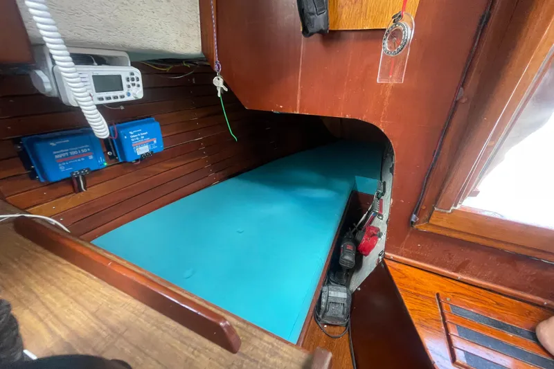 Slide: The Image of Interior of a 1987 Hallberg-Rassy Monsun 31 sailboat, featuring navigation equipment and a blue berth. - 12
