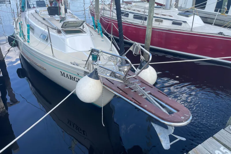 The Image of 1987 Hallberg-Rassy Monsun 31 sailboat docked, featuring a wooden bowsprit and fenders. - 0