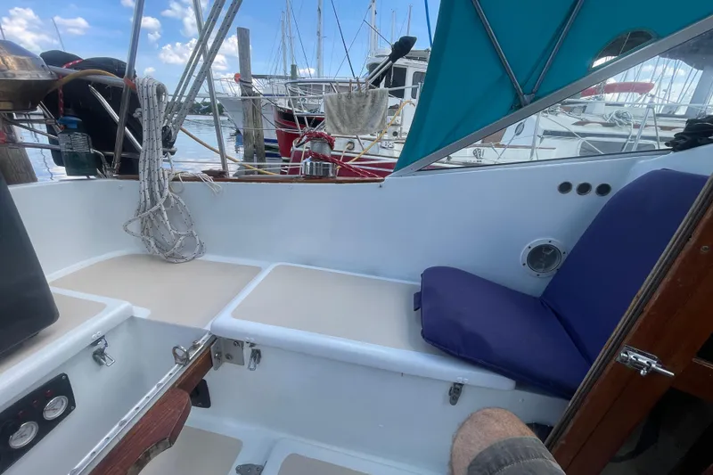 Slide: The Image of Cockpit of 1987 Hallberg-Rassy Monsun 31 sailboat with blue canopy and docked boats in background. - 10