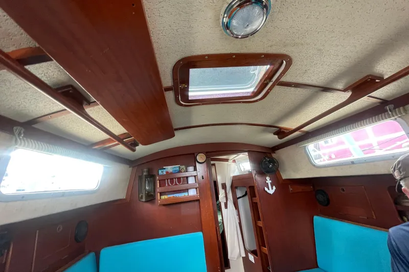 Slide: The Image of Interior of 1987 Hallberg-Rassy Monsun 31 sailboat, featuring wooden paneling and blue seating. - 15