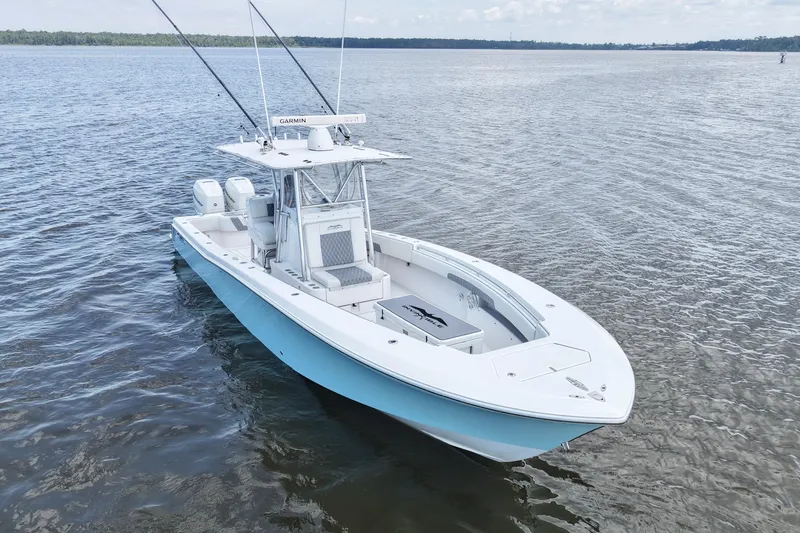 Slide: The Image of 2008 Invincible 33 Open Fisherman boat on calm water, featuring dual engines and fishing rods. - 14