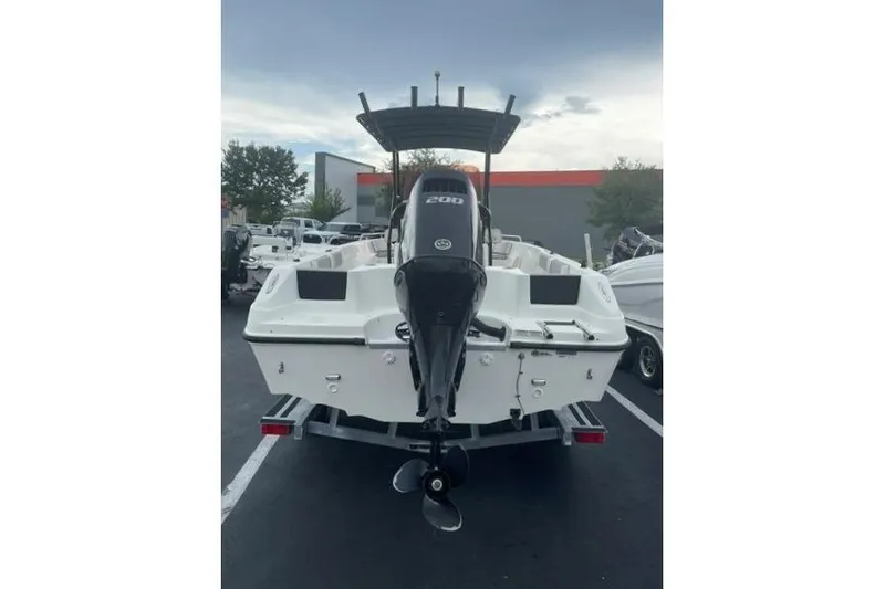Slide: The Image of 2024 Key Largo 2100 CCW boat with powerful outboard motor, parked outdoors. - 2