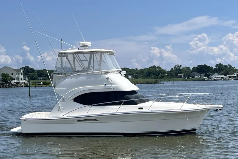 The Image of 2007 Riviera 33 Flybridge yacht on calm water with scenic background. - 0