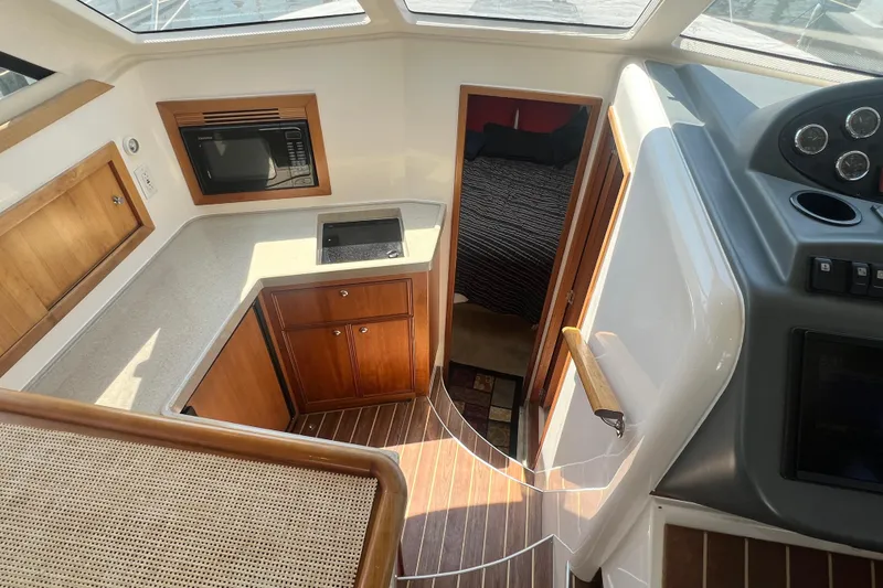 Slide: The Image of 2007 Riviera 33 Flybridge interior with kitchenette, microwave, and cozy cabin view. - 19