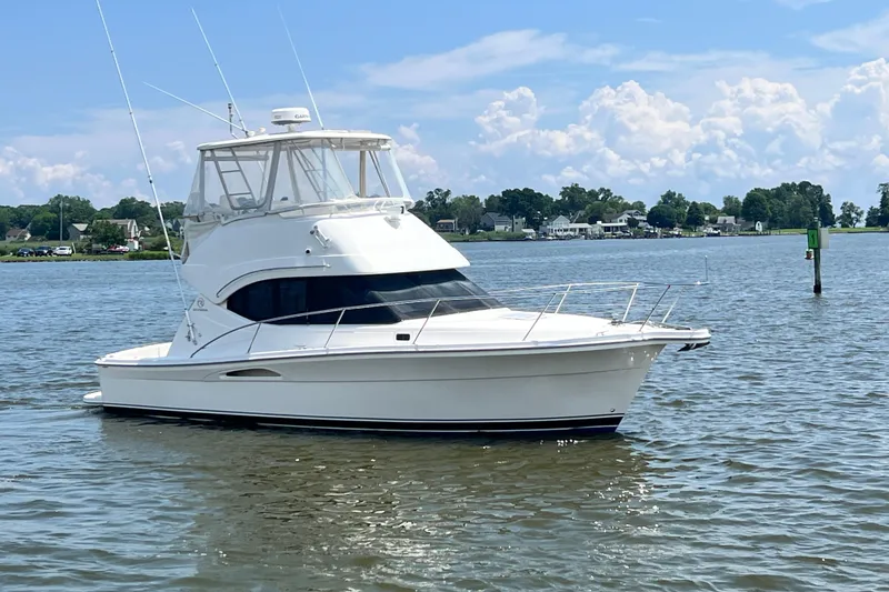 Slide: The Image of 2007 Riviera 33 Flybridge yacht on calm water under a blue sky. - 2