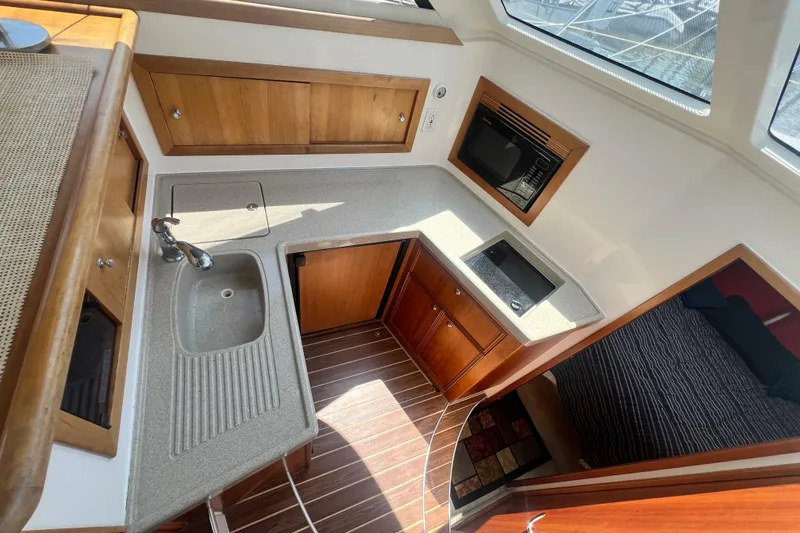 Slide: The Image of 2007 Riviera 33 Flybridge yacht kitchen with sink, stove, and wooden cabinetry. - 22