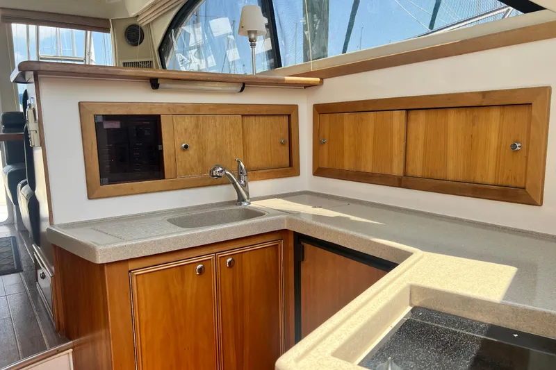 Slide: The Image of 2007 Riviera 33 Flybridge yacht interior kitchen with wooden cabinets and sink. - 23