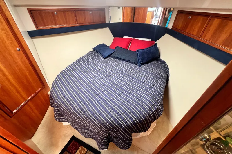 Slide: The Image of Cozy bedroom in 2007 Riviera 33 Flybridge yacht with striped bedding and wooden cabinets. - 26