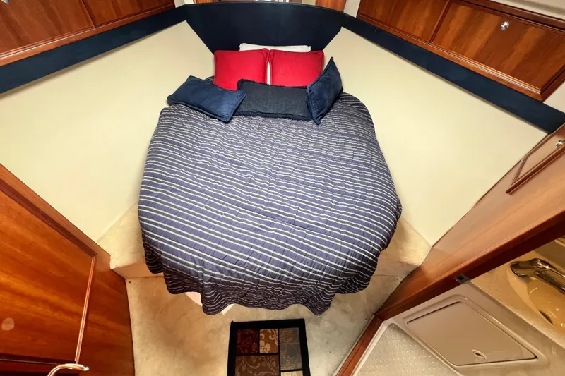 Slide: The Image of Cozy bedroom in 2007 Riviera 33 Flybridge yacht with striped bedding and wooden cabinetry. - 27