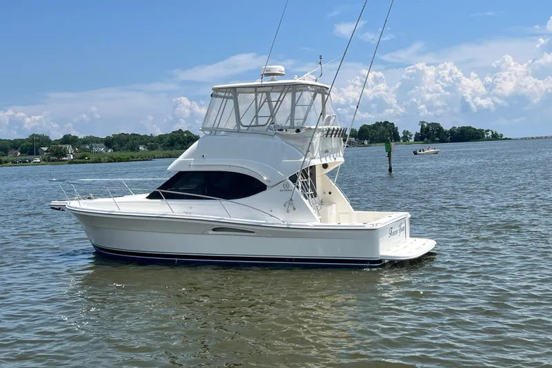 Slide: The Image of 2007 Riviera 33 Flybridge yacht on calm water under a clear sky. - 4