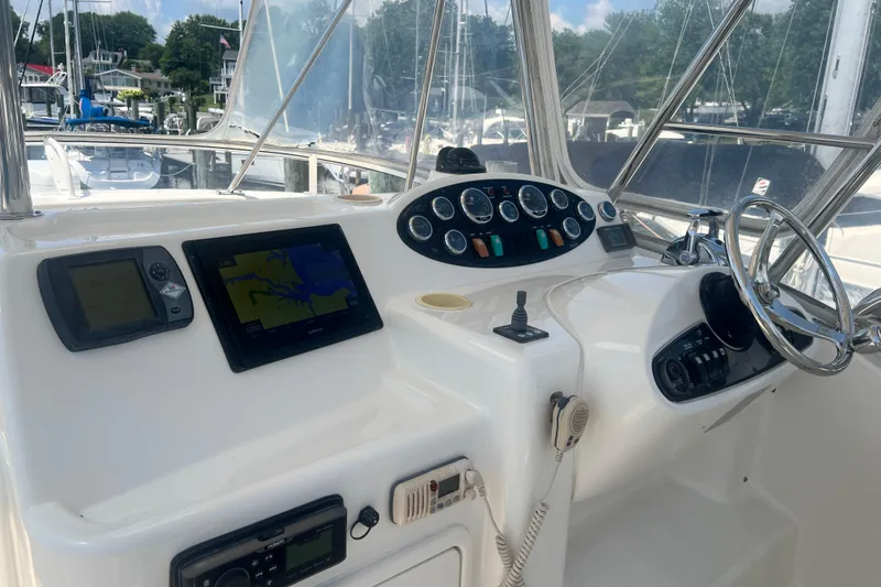 Slide: The Image of 2007 Riviera 33 Flybridge helm with navigation screens and controls in a marina setting. - 43