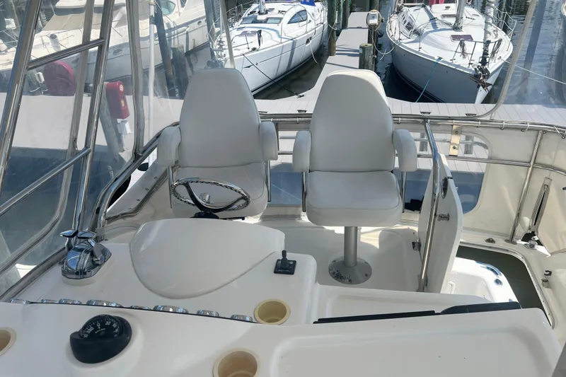 Slide: The Image of Flybridge of 2007 Riviera 33 yacht with dual white captain chairs and marina view. - 47