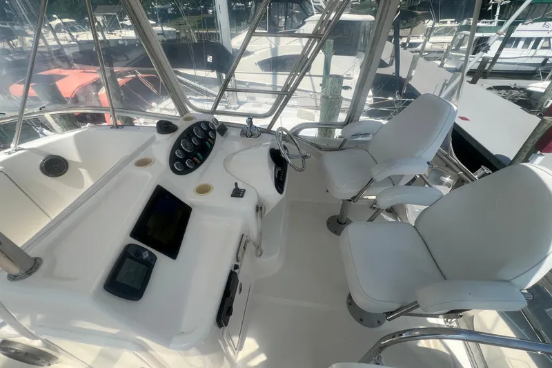 Slide: The Image of 2007 Riviera 33 Flybridge helm with dual white captain chairs and control panel. - 48