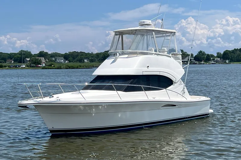 Slide: The Image of 2007 Riviera 33 Flybridge yacht on calm water under a blue sky. - 6