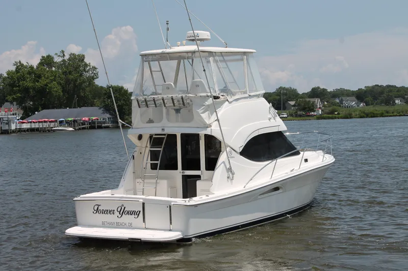Slide: The Image of 2007 Riviera 33 Flybridge yacht named "Forever Young" on a serene river. - 8