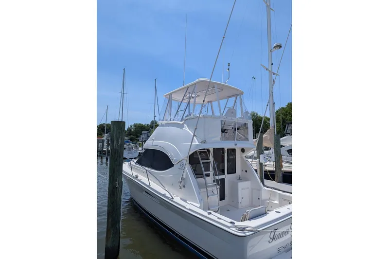 Slide: The Image of 2007 Riviera 33 Flybridge yacht docked at marina under clear blue sky. - 57