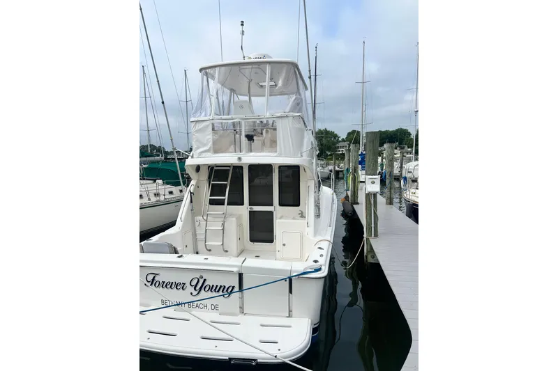 Slide: The Image of 2007 Riviera 33 Flybridge yacht docked, named "Forever Young," at a marina. - 56