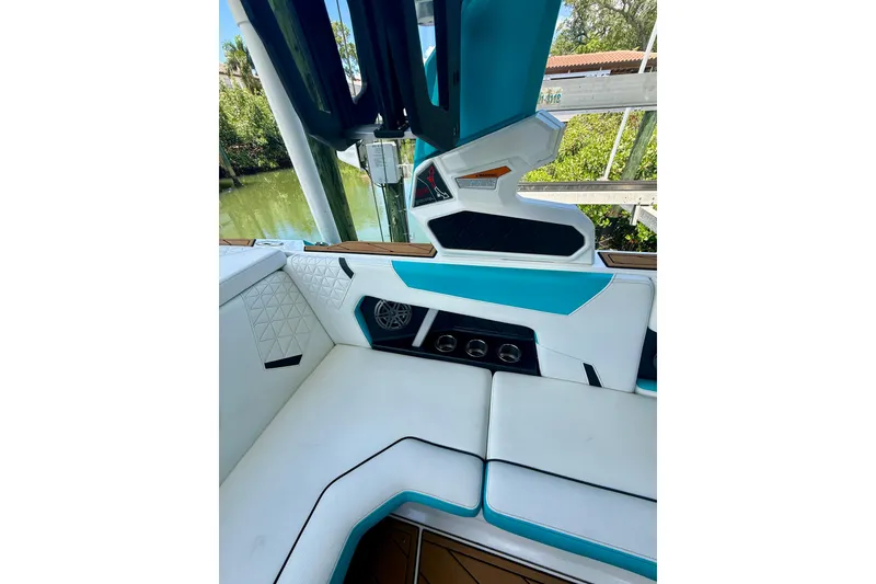 Slide: The Image of 2024 Nautique Super Air Nautique GS20 interior with white and teal seating, cup holders, and speaker. - 10