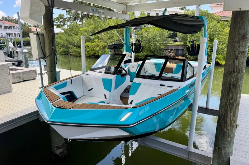 Slide: The Image of 2024 Nautique Super Air Nautique GS20 boat in vibrant blue, docked on a lift. - 19