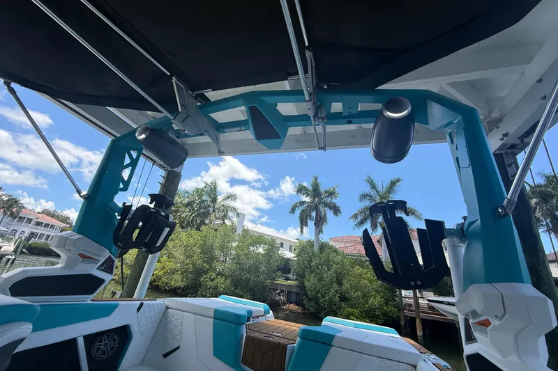 Slide: The Image of 2024 Nautique Super Air Nautique GS20 interior with speakers and wakeboard racks, under sunny sky. - 23