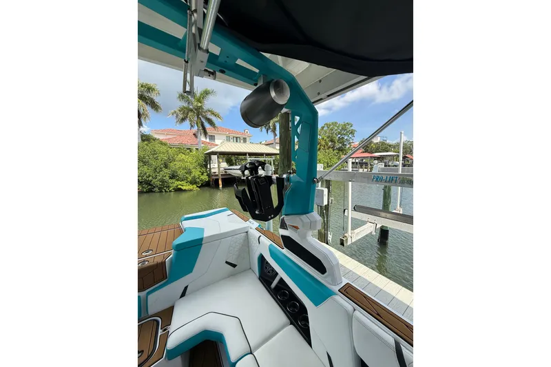 Slide: The Image of 2024 Nautique Super Air Nautique GS20 interior with teal accents, docked by waterfront homes. - 24