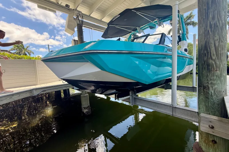 Slide: The Image of 2024 Nautique Super Air Nautique GS20 boat on lift, vibrant blue color, sunny day. - 3