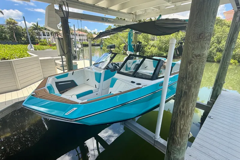 Slide: The Image of 2024 Nautique Super Air Nautique GS20 boat docked under a canopy, vibrant blue exterior. - 35