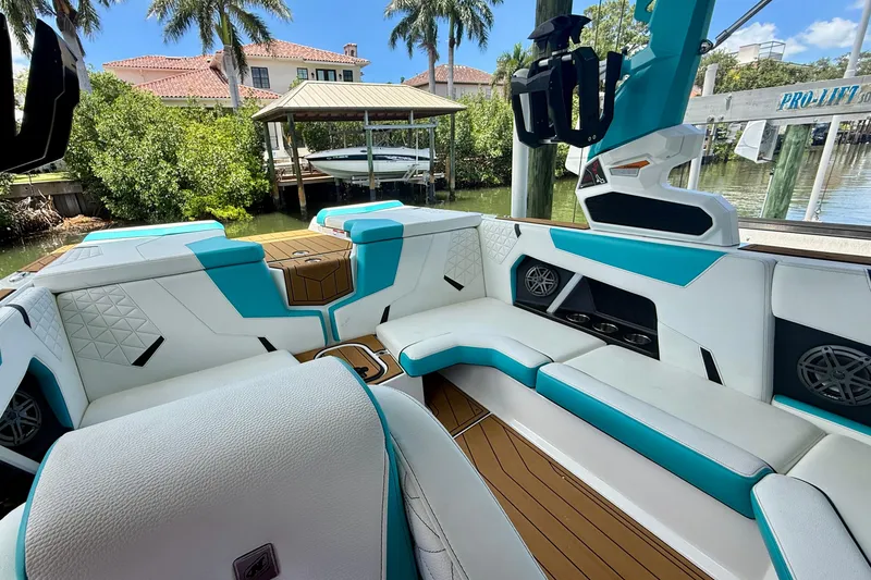 Slide: The Image of 2024 Nautique Super Air Nautique GS20 interior with teal and white seating, docked near waterfront homes. - 9