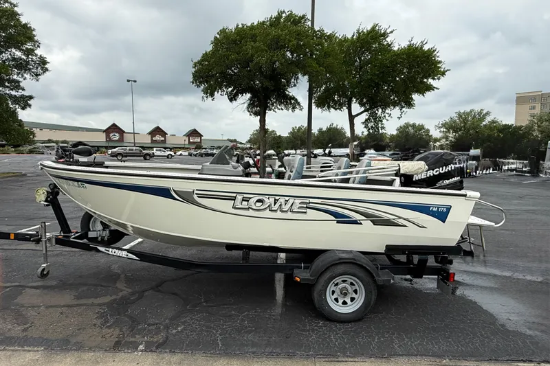 Slide: The Image of 2011 Lowe Fishing Machine 175 boat on trailer in parking lot. - 1