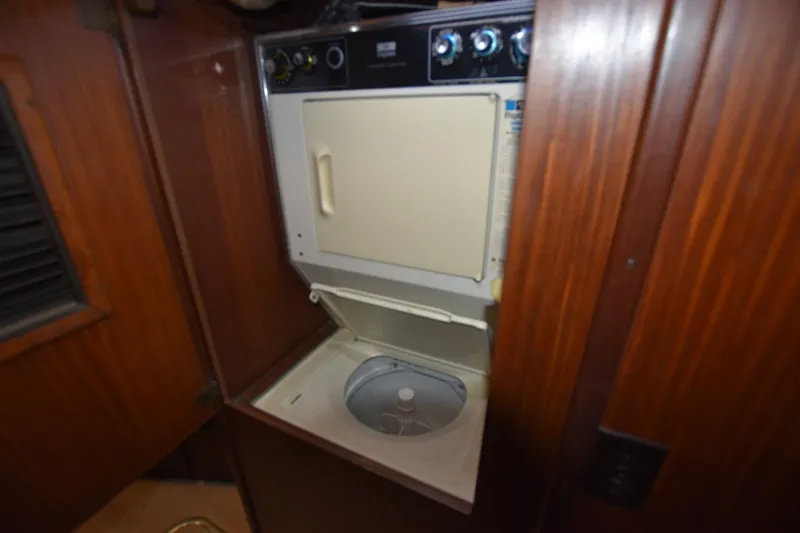 Slide: The Image of Compact laundry unit inside 1983 Hatteras 50 Convertible yacht, featuring wood paneling. - 24