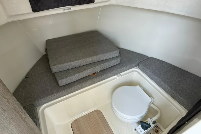Slide: The Image of 2025 Bayliner Trophy T23 Pilothouse interior with cushions and compact marine toilet. - 33