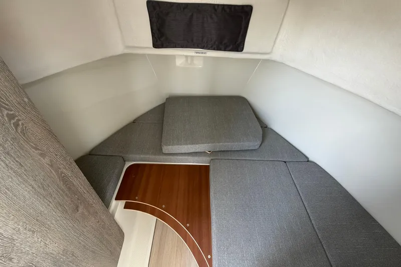 Slide: The Image of 2025 Bayliner Trophy T23 Pilothouse cabin interior with gray cushions and wooden flooring. - 31