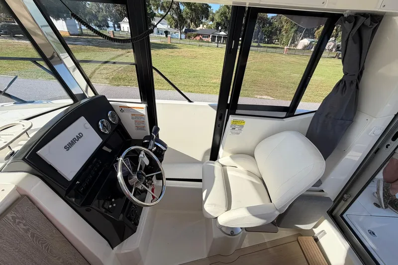 Slide: The Image of 2025 Bayliner Trophy T23 Pilothouse interior with steering wheel and Simrad display. - 22