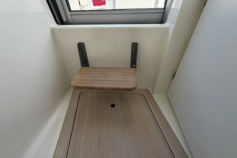 Slide: The Image of 2025 Bayliner Trophy T23 Pilothouse interior with foldable wooden seat and window. - 15