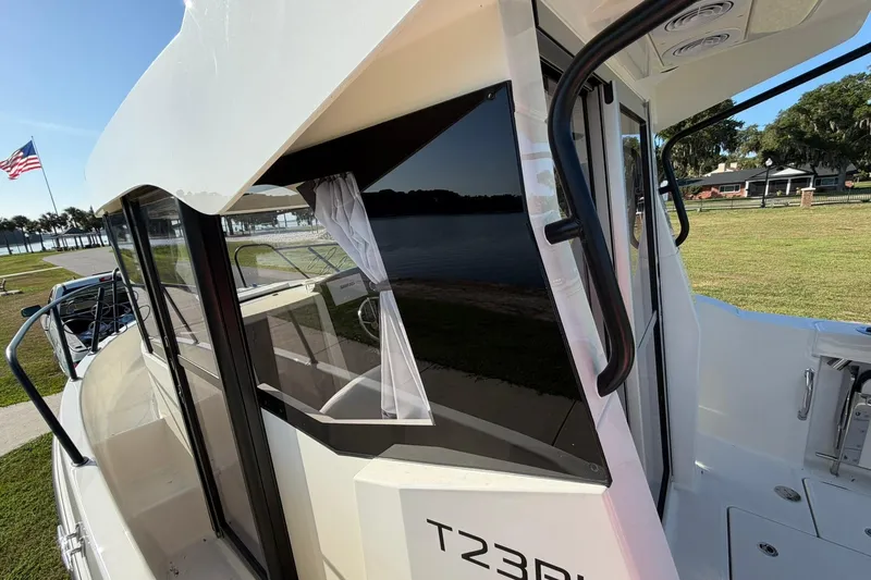 Slide: The Image of 2025 Bayliner Trophy T23 Pilothouse boat docked near a scenic waterfront. - 57