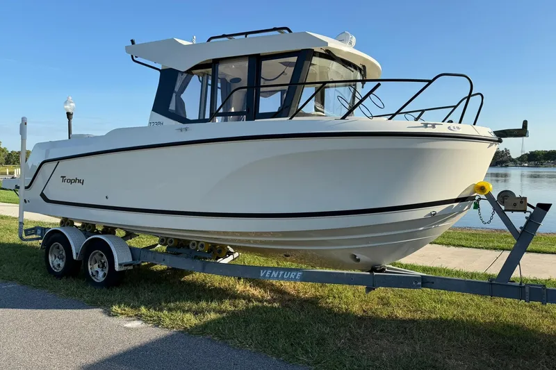 The Image of 2025 Bayliner Trophy T23 Pilothouse boat on trailer by waterfront. - 0