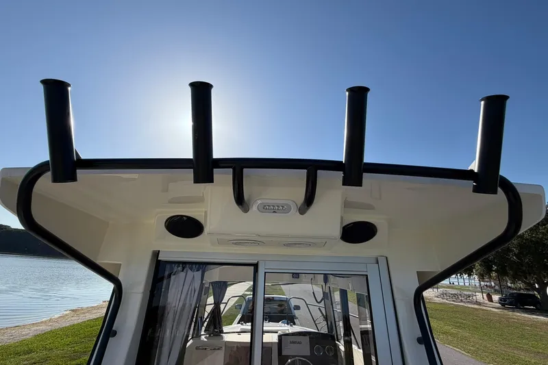 Slide: The Image of 2025 Bayliner Trophy T23 Pilothouse boat with rod holders, viewed from the rear. - 54