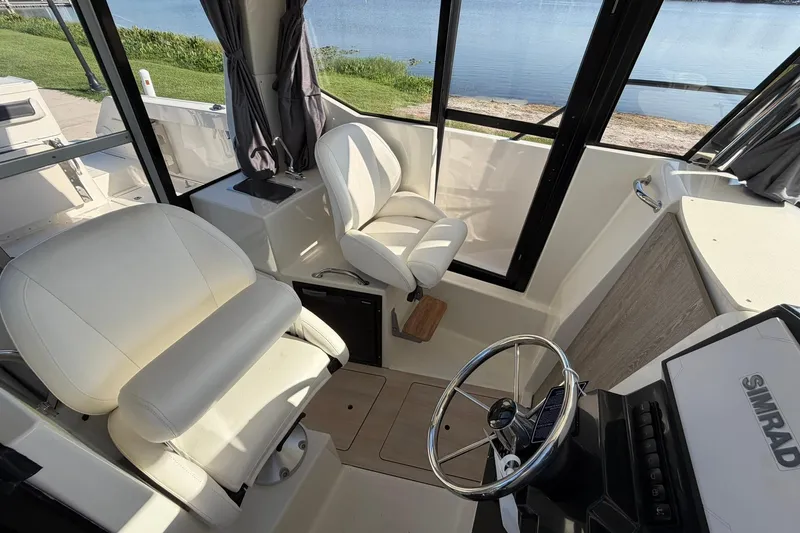 Slide: The Image of Interior of 2025 Bayliner Trophy T23 Pilothouse with steering wheel and seating, overlooking water. - 35