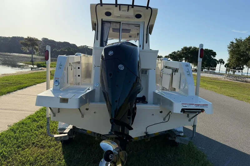 Slide: The Image of 2025 Bayliner Trophy T23 Pilothouse boat with outboard motor, parked near a scenic waterfront. - 63