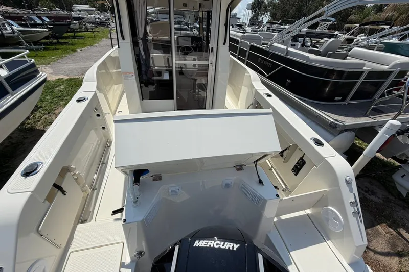 Slide: The Image of 2025 Bayliner Trophy T23 Pilothouse boat interior with Mercury engine, docked among other boats. - 49