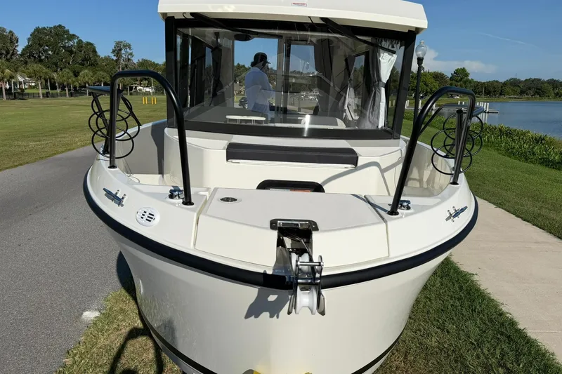Slide: The Image of 2025 Bayliner Trophy T23 Pilothouse boat docked near a scenic lake. - 1
